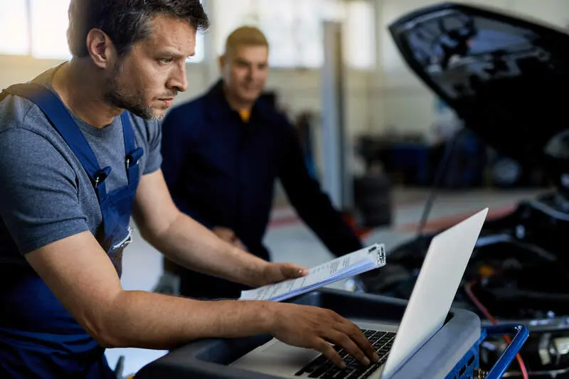 auto repairman working computer while doing car diagnostic.jpg